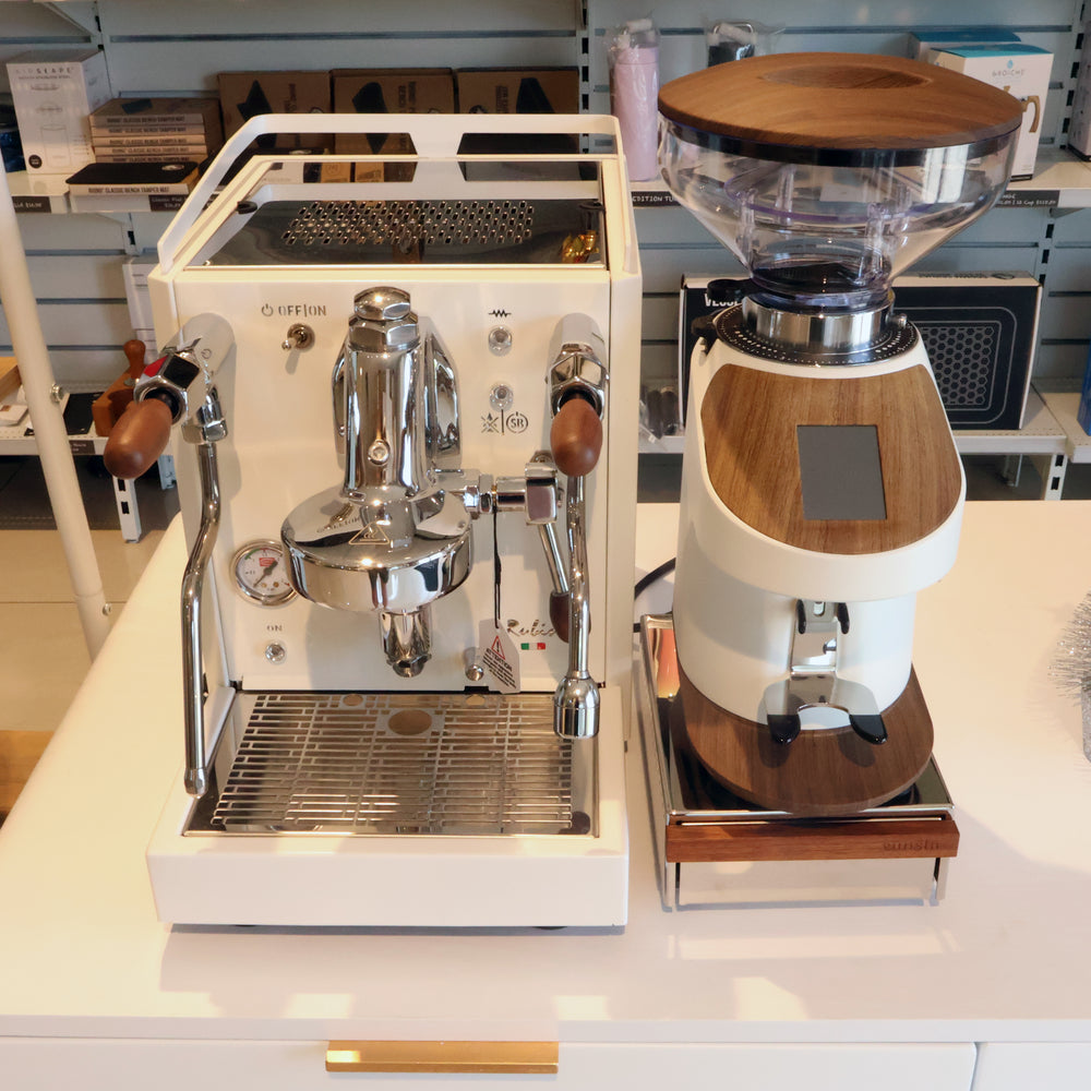 White espresso machine with wooden accents on a white countertop.